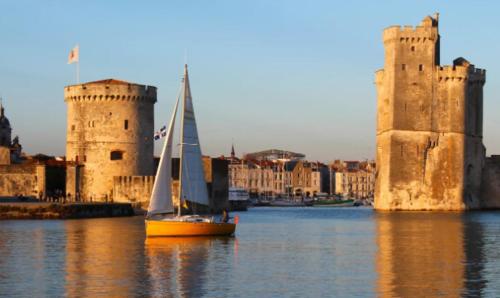 a sailboat in the water in front of a castle at Appartement proche de la plage des minimes in La Rochelle