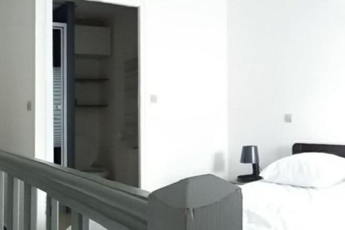 a white bedroom with a bed and a lamp at Appartement proche de la plage des minimes in La Rochelle