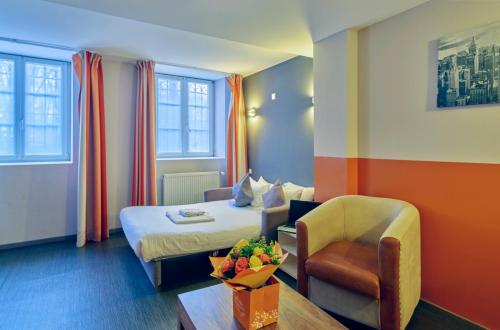 a hotel room with a bed and a chair at Adonis Hotel Strasbourg in Strasbourg