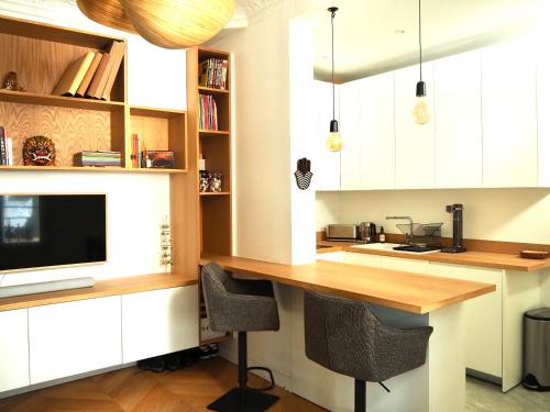 a kitchen with white cabinets and a desk with a television at Le Bijou in Neuilly-sur-Seine