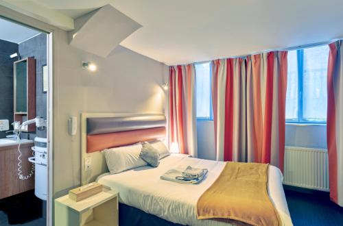 a hotel room with a bed and a window at Adonis Hotel Strasbourg in Strasbourg
