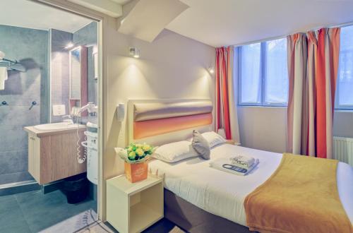 a hotel room with a bed and a bathroom at Adonis Hotel Strasbourg in Strasbourg