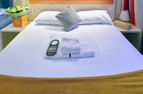 a white bed with a remote control and underwear on it at Adonis Hotel Strasbourg in Strasbourg