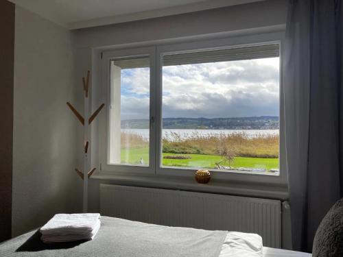 a bedroom with a window with a view of the water at Seeluft direkt am Wasser in Reichenau