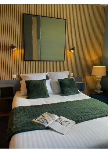 une chambre d'hôtel avec un lit avec un livre dessus dans l'établissement Hôtel des Pins, à Jullouville