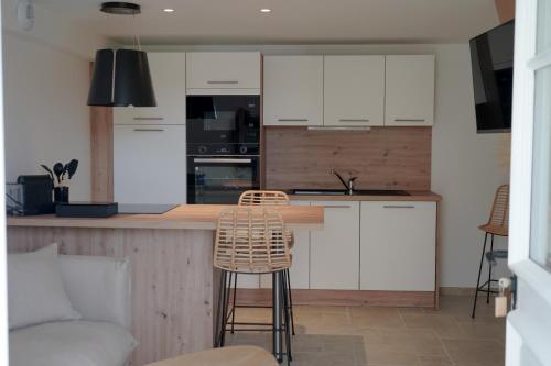 a kitchen with white cabinets and a bar with a chair at Château de l'insolas in Villeneuve-lès-Avignon