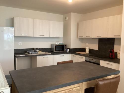 une cuisine avec des armoires blanches et un comptoir noir dans l'établissement Duplex à 10 min de La Rochelle, à La Rochelle