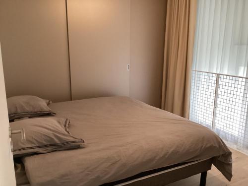 un lit dans une chambre avec une grande fenêtre dans l'établissement Duplex à 10 min de La Rochelle, à La Rochelle