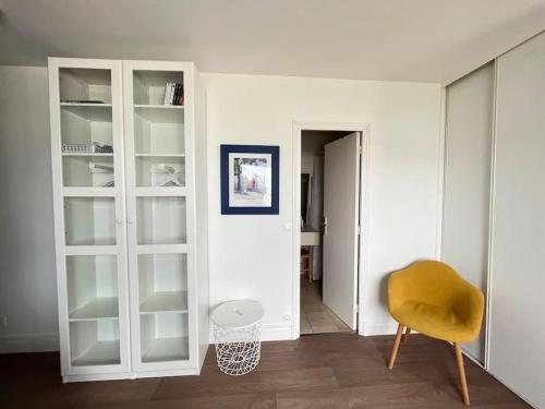 een kamer met witte kasten en een gele stoel bij Le Sextant Conciergerie Yourhosthelper in Larmor-Plage