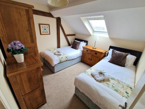 a bedroom with two beds and a window at Cowman's Cottage in Leighton Buzzard