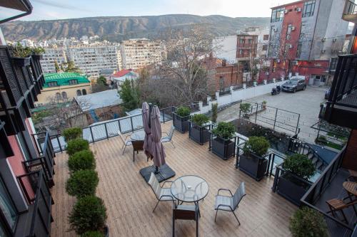 a balcony with tables and chairs and a view of a city at Alliance Hotel in Tbilisi City