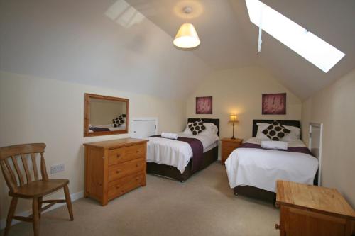 a attic bedroom with two beds and a mirror at Grooms Cottage in Leighton Buzzard