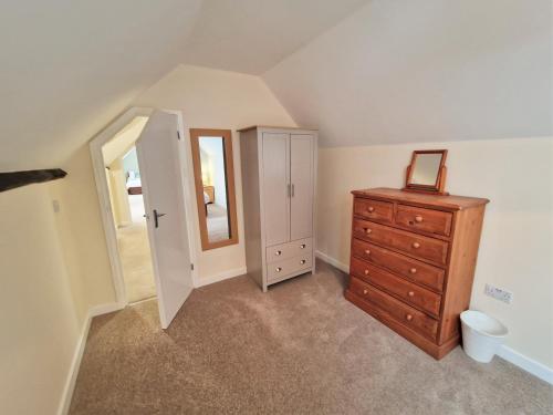 an attic room with a dresser and a mirror at The Homestead in Leighton Buzzard