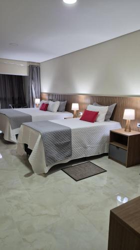 two beds in a large room with two lamps at Pousada Recanto Família Suíte com Hidro in Paraty