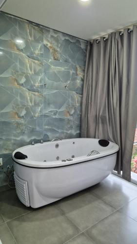 a bath tub in a bathroom with a stone wall at Pousada Recanto Família Suíte com Hidro in Paraty