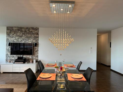 a dining room with a table with chairs and a chandelier at Oasis de Sérénité au Cœur de Lausanne : Appartement Spacieux in Le Mont-sur-Lausanne