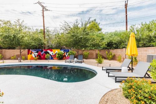 a backyard with a pool with chairs and an umbrella at Heated Pool Outdoor Kitchen Patio Modern Design in Scottsdale