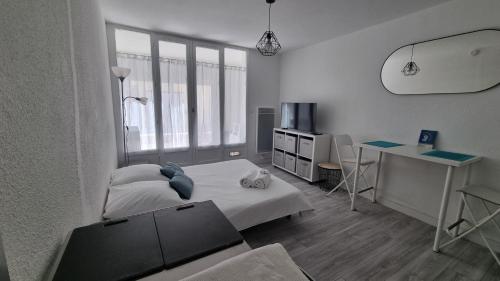 Habitación blanca con cama, escritorio y escritorio. en Le petit Brigantin, en Gruissan