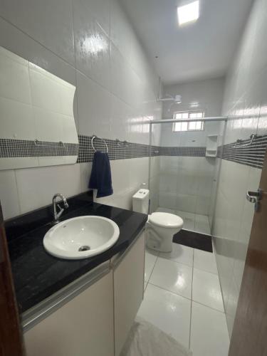La salle de bains blanche est pourvue d'un lavabo et de toilettes. dans l'établissement Até 08 pessoas, próximo ao shopping com garagem, à Petrolina