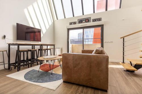 a living room with a couch and a flat screen tv at L'Escapade Paris in Le Kremlin-Bicêtre