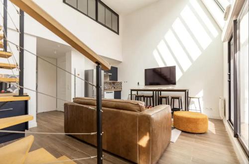 a living room with a couch and a tv at L'Escapade Paris in Le Kremlin-Bicêtre
