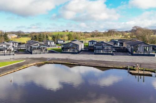 eine Reihe von Häusern neben einem Wasserkörper in der Unterkunft Arranview Lochside Pods & Lodges all with private Hot-tubs in Fenwick