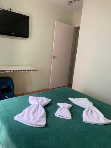 three white towels sitting on top of a bed at HOTEL PORTO FINO in Pontal do Paraná
