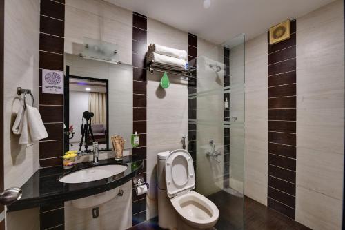 een badkamer met een toilet, een wastafel en een douche bij Click Hotel Yuvraj in Surat