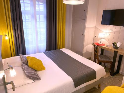 a bedroom with a bed and a desk and a television at La Vieille Auberge du Lac in Saint-Agnan