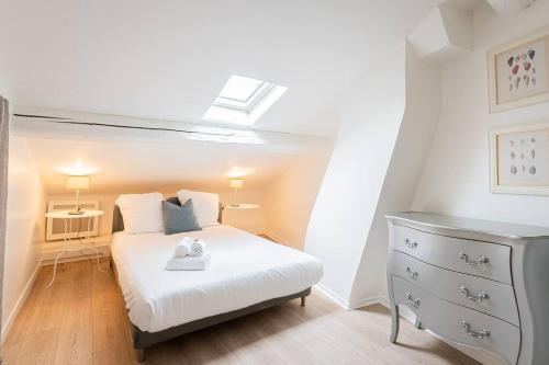 Cette petite chambre comprend un lit blanc et une commode. dans l'établissement Le Tiffany, Beau T2 en Duplex, Beaux Arts, à Montpellier