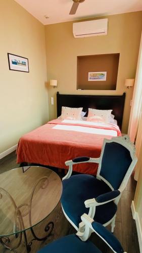 a bedroom with a bed with two chairs and a table at Hôtel La Villa Patricia - Charme et Tradition in Villefranche-sur-Mer