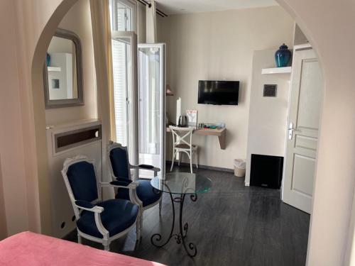 Cette chambre dispose d'une table, de chaises et d'un bureau. dans l'établissement Hôtel La Villa Patricia - Charme et Tradition, à Villefranche-sur-Mer