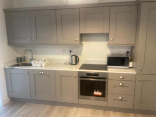 uma cozinha com armários brancos e um forno com placa de fogão em Luxury King Size Bed Sandyford Mountain View em Sandyford