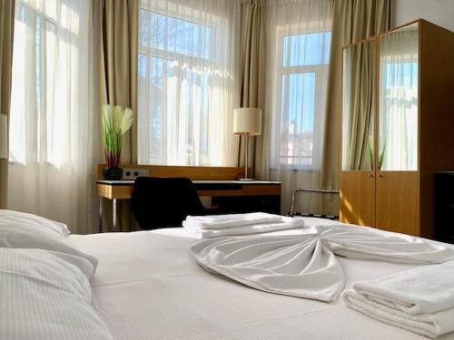 a bedroom with a bed with white sheets and windows at Corso in Eforie Sud