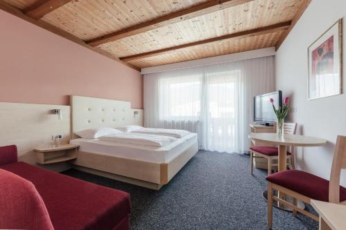 a bedroom with a bed and a tv and a couch at Hotel Garni Sirmian in Merano