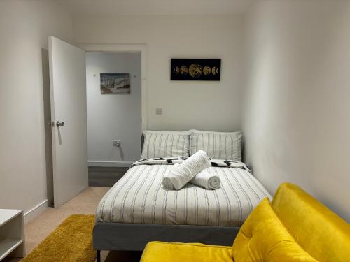 a bedroom with a bed and a yellow couch at Double room with shares bathroom in Woolwich