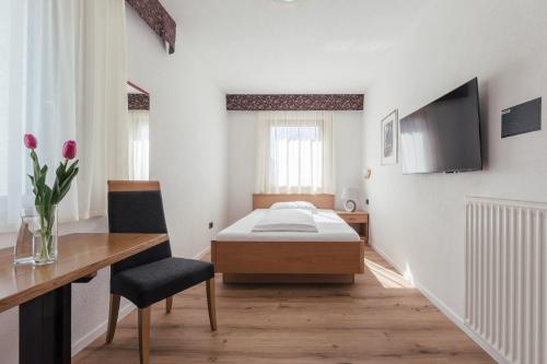 a bedroom with a bed and a desk and a television at Hotel Garni Sirmian in Merano