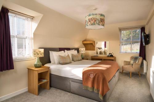 a bedroom with a bed and a chair and windows at Plockton Inn in Plockton