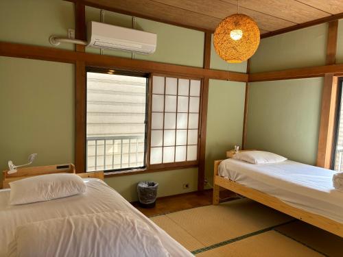 two beds in a room with two windows at 15min to Haneda Airport - Homies House Kamata for up to 9 guests in Tokyo
