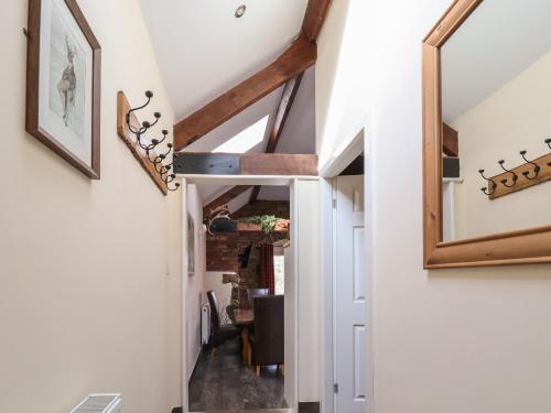 a hallway with white walls and a ceiling with beams at Gamekeepers Cottage in St Asaph