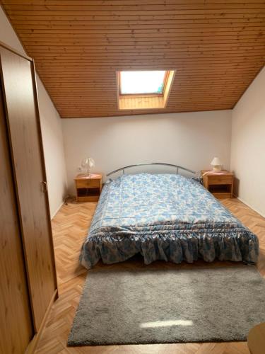 a bedroom with a bed with a blue comforter and a window at VIL'LAGUNA Apartment with view of Balaton in Zánka