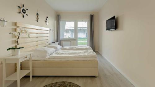 a white bedroom with a bed and a window at VacationClub - Leśna 12B Apartament 8 in Pobierowo