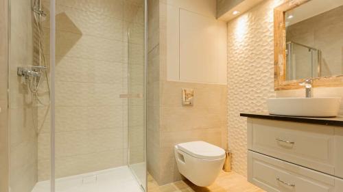 a bathroom with a shower and a toilet and a sink at VacationClub - Leśna 12B Apartament 8 in Pobierowo