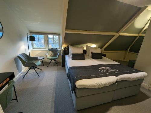 a bedroom with a bed and a desk and chairs at Landgoed De Uitkijk Hellendoorn in Hellendoorn