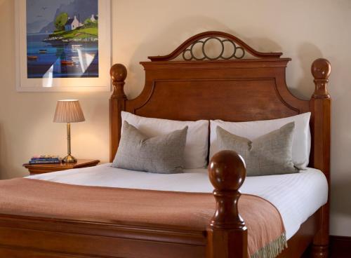 a bedroom with a bed with a wooden headboard and pillows at Plockton Inn in Plockton