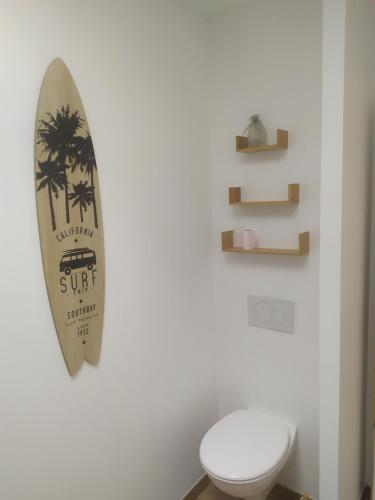 a bathroom with a surfboard on the wall next to a toilet at Maison de vacances cosy à La Baule in La Baule