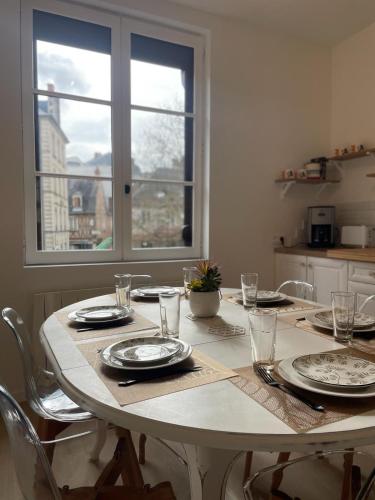 une table à manger avec des assiettes et des verres ainsi qu'une fenêtre dans l'établissement Triplex - 4 chambres - Centre historique, à Bourges