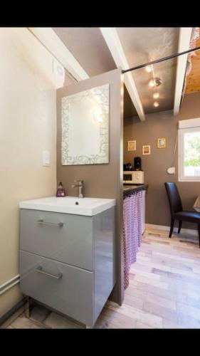 La salle de bains est pourvue d'un lavabo et d'un comptoir avec une chaise. dans l'établissement Saint-Jorioz, charmante maisonnette indépendante., à Saint-Jorioz