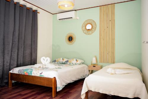 ein Schlafzimmer mit zwei Betten und einem Spiegel in der Unterkunft L'Hôtel Du Fleuve in Sinnamary