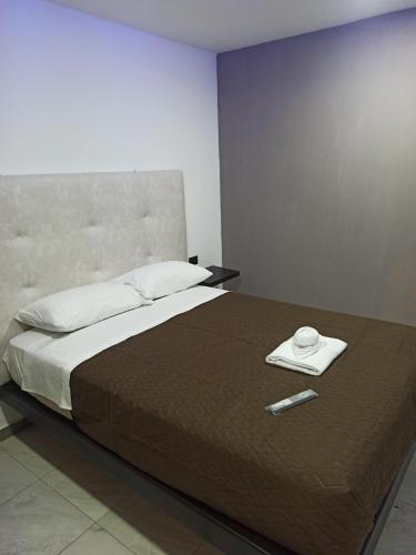 Hostal Zafiro في Sangolquí: غرفة نوم مع سرير مع ريموت كنترول عليه
